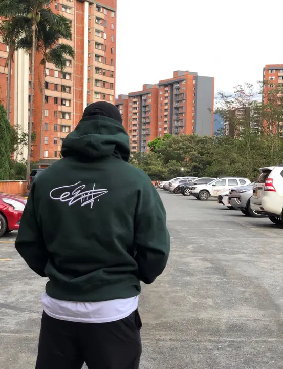 Modelo de espaldas con el Hoodie Signature Verde Bosque en una calle de Medellín
