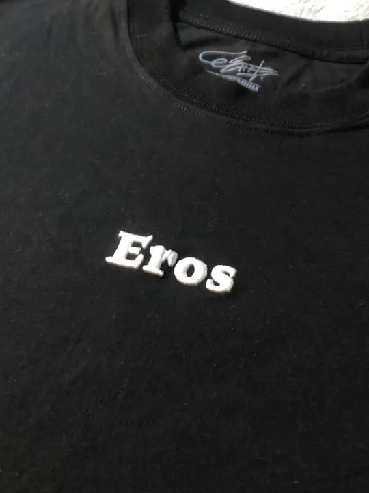 Primer plano de la palabra Eros en relieve blanco sobre la camiseta negra