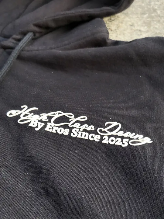Primer plano del estampado High Class Design, By Eros Since 2025, en el crop hoodie negro