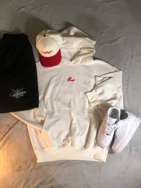 Hoodie Signature Crema con “Eros” rojo, pantaloneta negra y gorra crema con visera roja